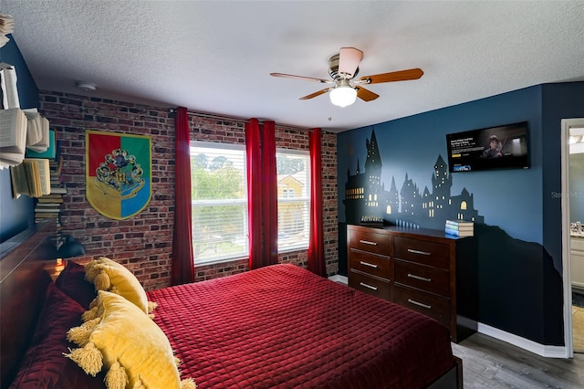 bedroom featuring a textured ceiling, ceiling fan, dark wood-type flooring, and brick wall