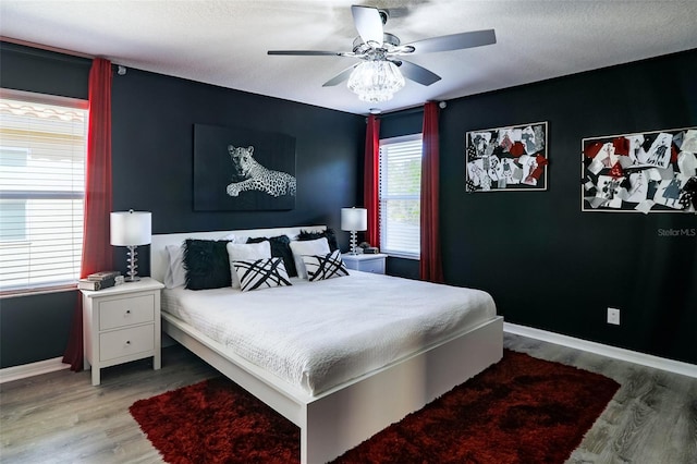 bedroom with ceiling fan, light hardwood / wood-style flooring, and a textured ceiling