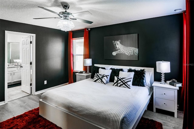 bedroom with a textured ceiling, ensuite bathroom, light hardwood / wood-style flooring, and ceiling fan