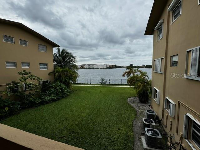 view of yard with a water view, fence, and central air condition unit