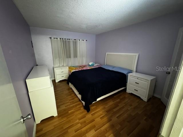 bedroom with dark hardwood / wood-style flooring and a textured ceiling