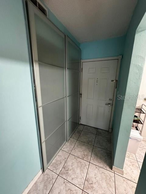 hallway featuring a textured ceiling and light tile patterned flooring