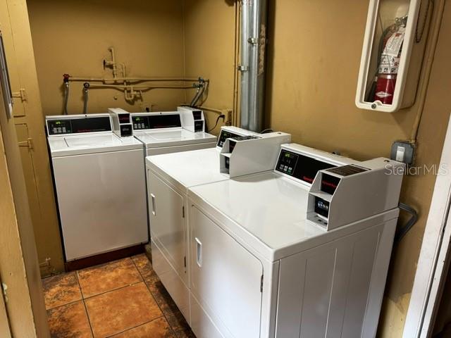 laundry room featuring washer and clothes dryer and dark tile patterned flooring