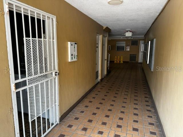 hallway featuring brick floor, a textured ceiling, and baseboards