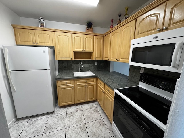 kitchen featuring light brown cabinetry, white appliances, backsplash, and a sink