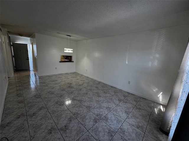 empty room featuring tile patterned flooring, baseboards, and a textured ceiling