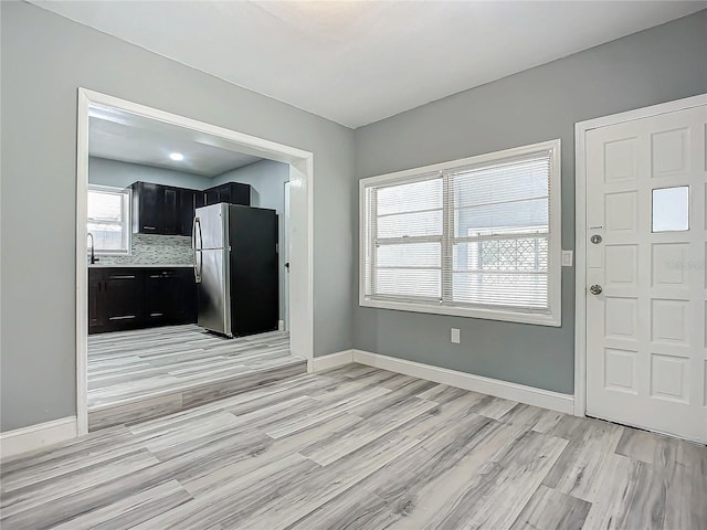 kitchen featuring decorative backsplash, light hardwood / wood-style floors, stainless steel refrigerator, and sink