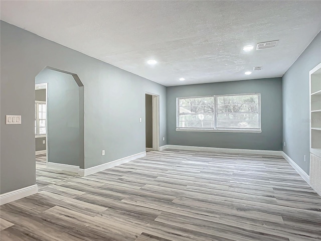 empty room featuring light wood-type flooring and a textured ceiling