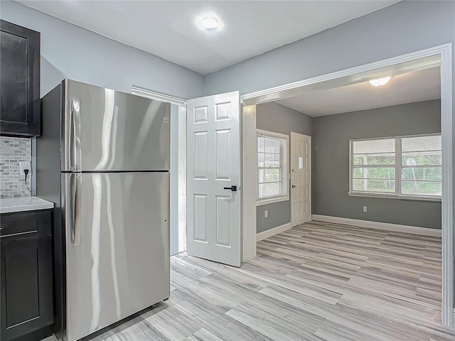 kitchen with light hardwood / wood-style flooring, stainless steel refrigerator, and tasteful backsplash