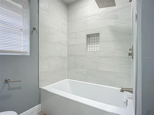 bathroom featuring toilet and tiled shower / bath