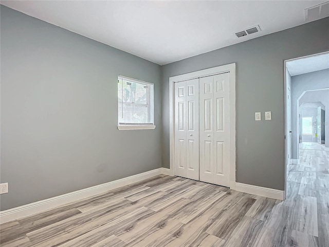 unfurnished bedroom featuring light wood-type flooring and a closet