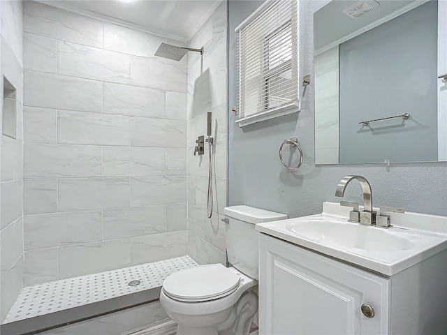 bathroom with a tile shower, vanity, and toilet