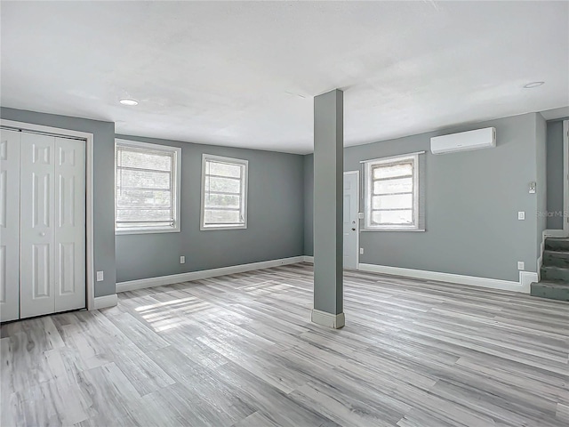 basement featuring light hardwood / wood-style floors and an AC wall unit