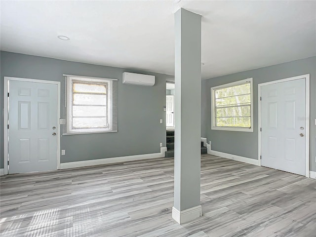 foyer entrance with light wood-type flooring, an AC wall unit, and a wealth of natural light