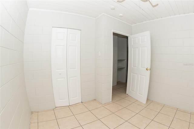 unfurnished bedroom featuring light tile patterned floors, a closet, crown molding, and ceiling fan