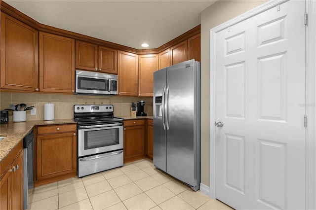 kitchen with stone counters, appliances with stainless steel finishes, backsplash, and light tile patterned floors