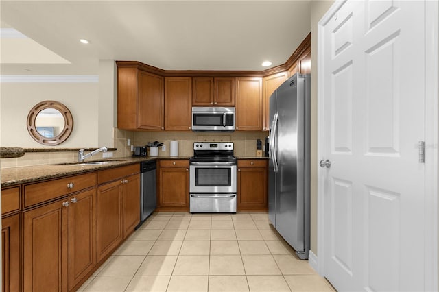 kitchen with dark stone counters, sink, ornamental molding, appliances with stainless steel finishes, and tasteful backsplash