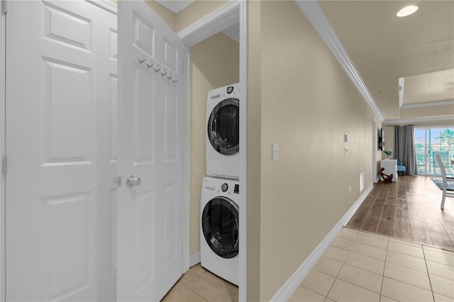 laundry room with stacked washing maching and dryer, light hardwood / wood-style flooring, and ornamental molding