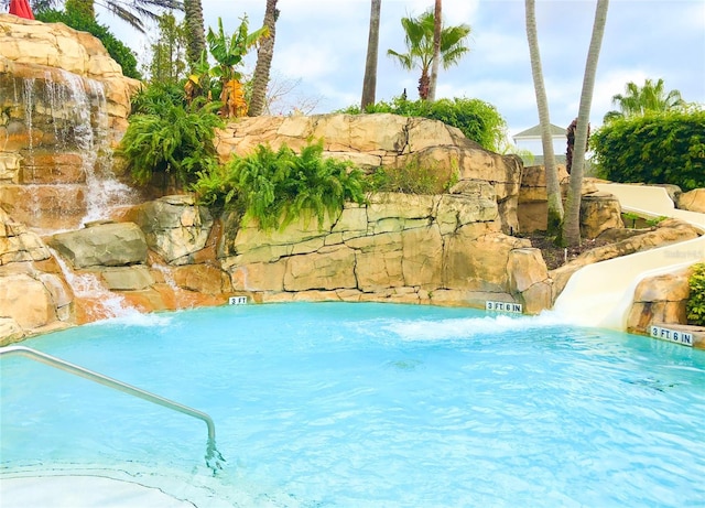 view of swimming pool with pool water feature and a water slide