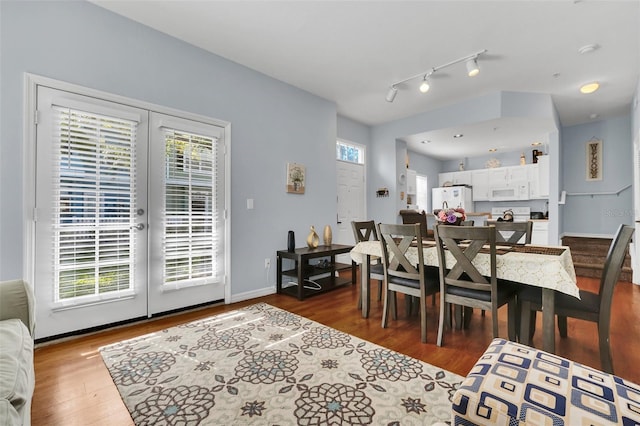 dining space featuring dark hardwood / wood-style floors, rail lighting, and french doors