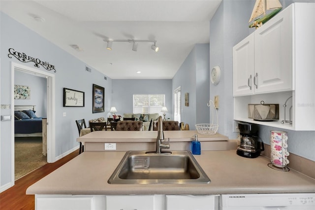 kitchen with sink, rail lighting, dishwasher, white cabinetry, and dark hardwood / wood-style flooring