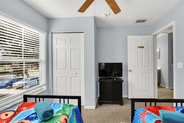 bedroom with ceiling fan, multiple windows, light carpet, and a closet