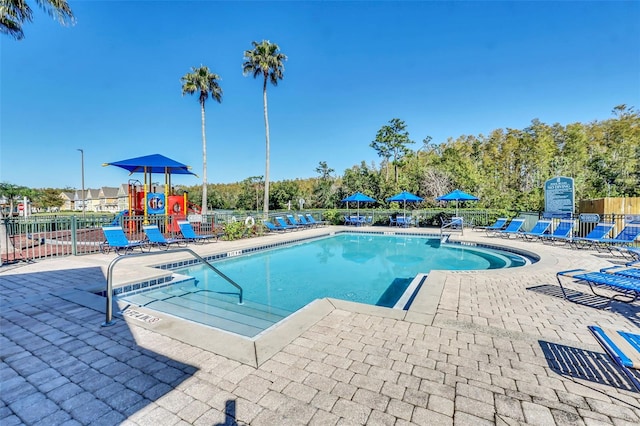 view of pool featuring a playground and a patio