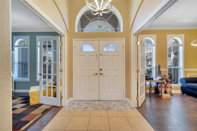 foyer featuring a notable chandelier, a healthy amount of sunlight, dark hardwood / wood-style flooring, and crown molding