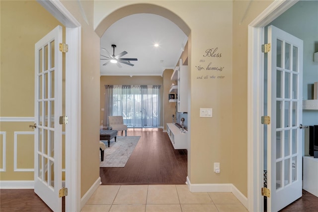 hallway featuring crown molding, light hardwood / wood-style flooring, and french doors