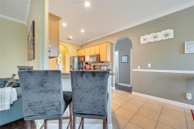 kitchen with appliances with stainless steel finishes, backsplash, ornamental molding, light brown cabinets, and light tile patterned floors