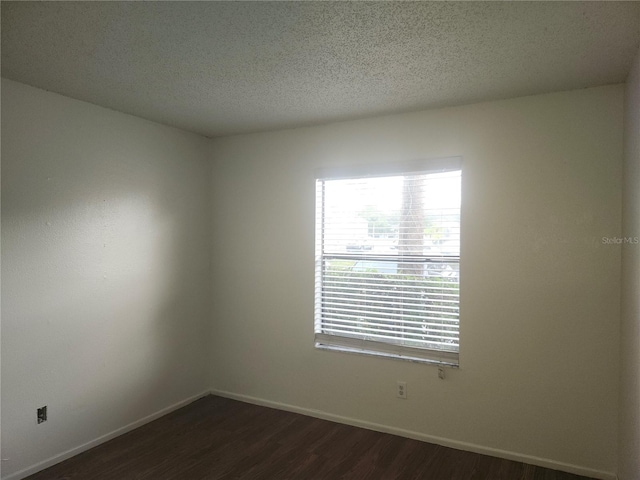 empty room featuring a textured ceiling and dark wood-type flooring