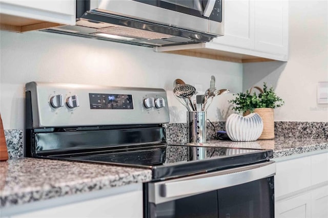 kitchen with white cabinets, appliances with stainless steel finishes, and light stone countertops