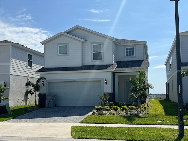 view of property featuring a garage and a front lawn