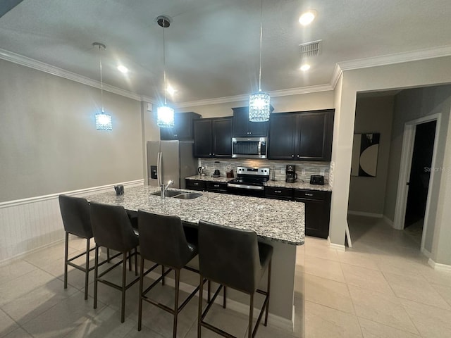 kitchen with appliances with stainless steel finishes, a kitchen island with sink, and a kitchen breakfast bar