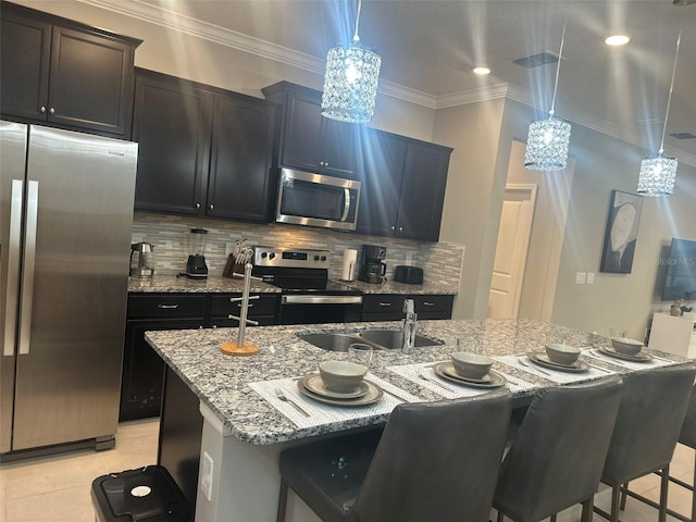 kitchen with pendant lighting, backsplash, stainless steel appliances, and a kitchen island with sink