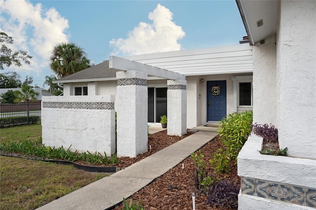 doorway to property featuring a yard and a pergola