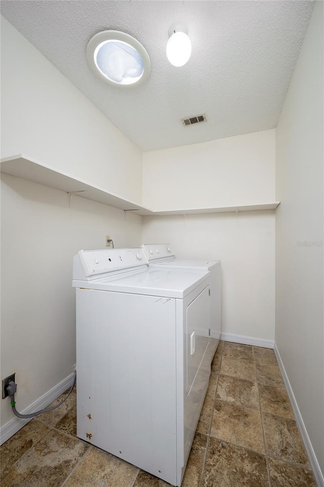 washroom with washing machine and clothes dryer and a textured ceiling