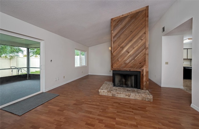 unfurnished living room featuring vaulted ceiling, a fireplace, a textured ceiling, and hardwood / wood-style flooring