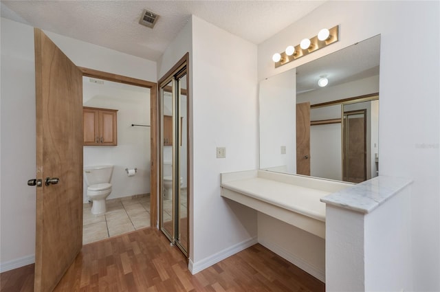 bathroom with hardwood / wood-style floors, a textured ceiling, and toilet