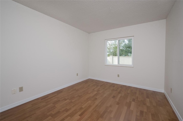 unfurnished room with hardwood / wood-style flooring and a textured ceiling