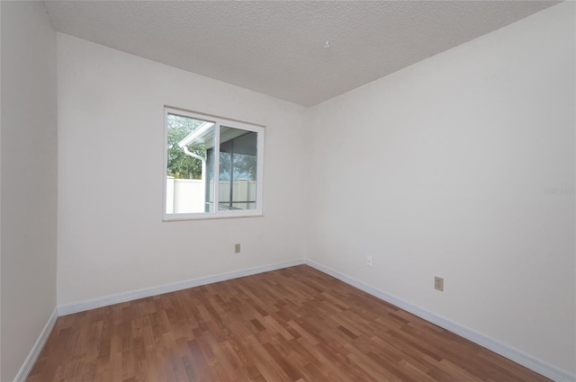 empty room featuring wood-type flooring and a textured ceiling