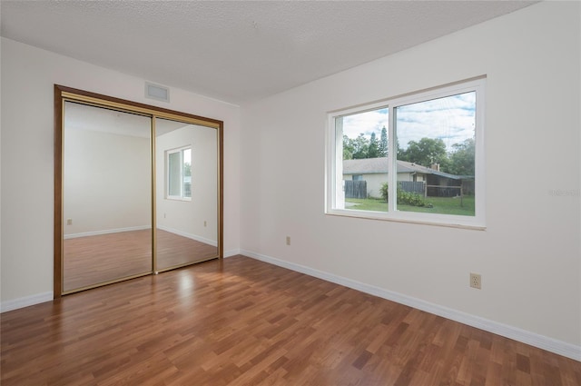 unfurnished bedroom with hardwood / wood-style flooring, a textured ceiling, and a closet