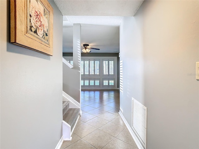 hall featuring light tile patterned flooring and a textured ceiling