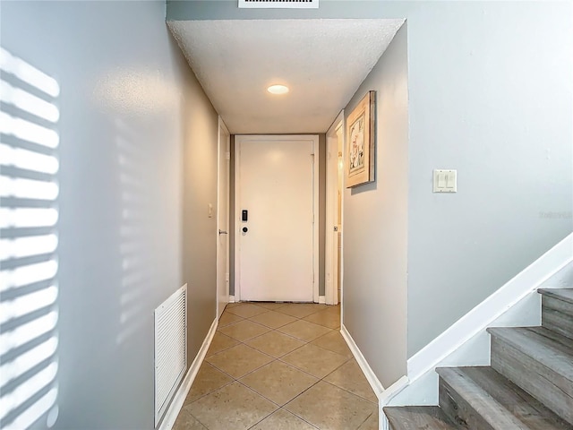 doorway to outside with light tile patterned floors and a textured ceiling