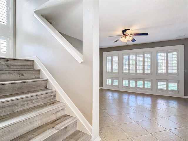 stairway featuring ceiling fan and tile patterned flooring