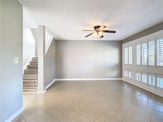 tiled spare room featuring a textured ceiling and ceiling fan