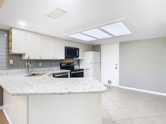 kitchen featuring decorative backsplash, appliances with stainless steel finishes, a skylight, sink, and white cabinetry