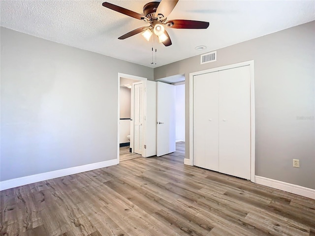 unfurnished bedroom with ceiling fan, a closet, a textured ceiling, and light wood-type flooring