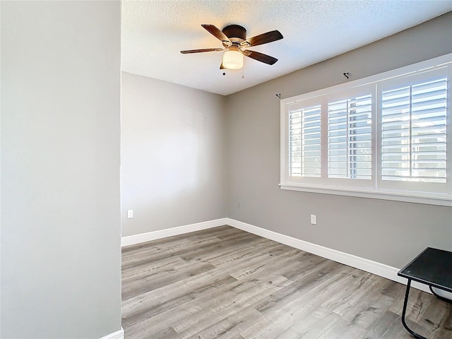 unfurnished room with ceiling fan, a textured ceiling, and light wood-type flooring