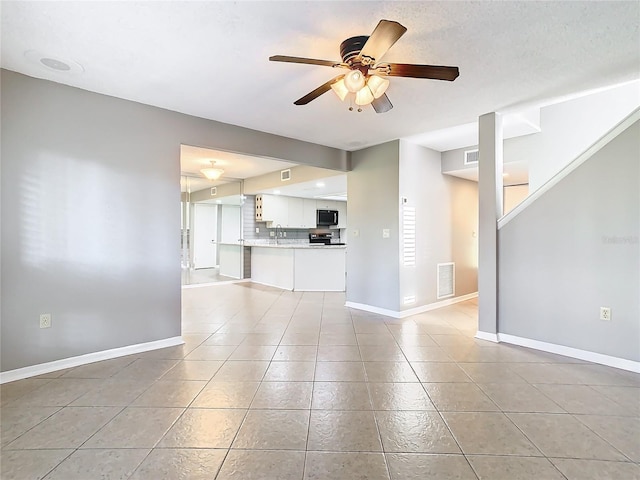 unfurnished living room with light tile patterned floors, a textured ceiling, ceiling fan, and sink